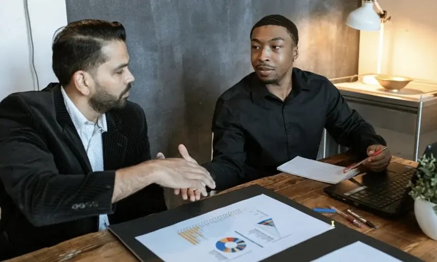 Two businessmen shaking hands while looking at each other.