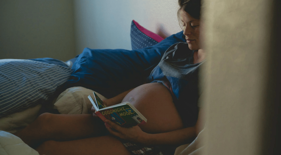 pregnant woman reading a children's book to her baby