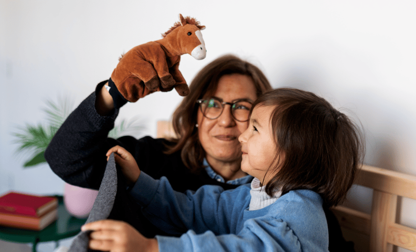Grandmother holding up a horse toy to her granddaughter