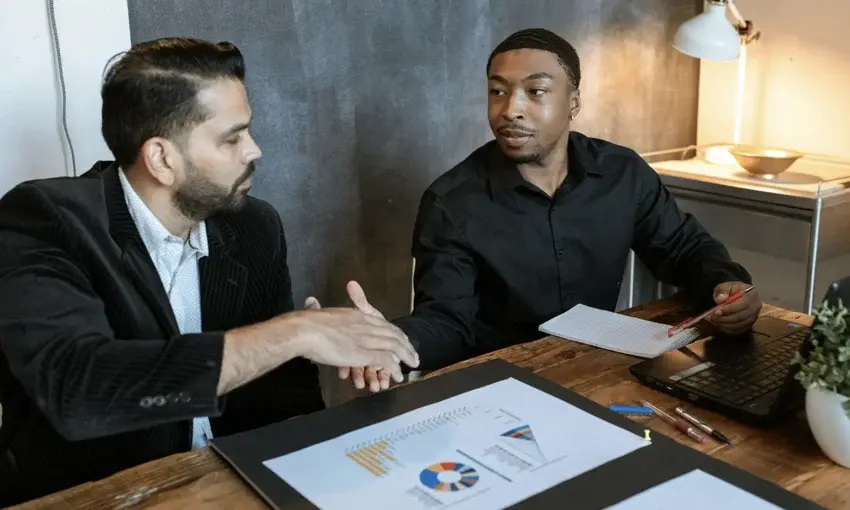 Two businessmen shaking hands while looking at each other.