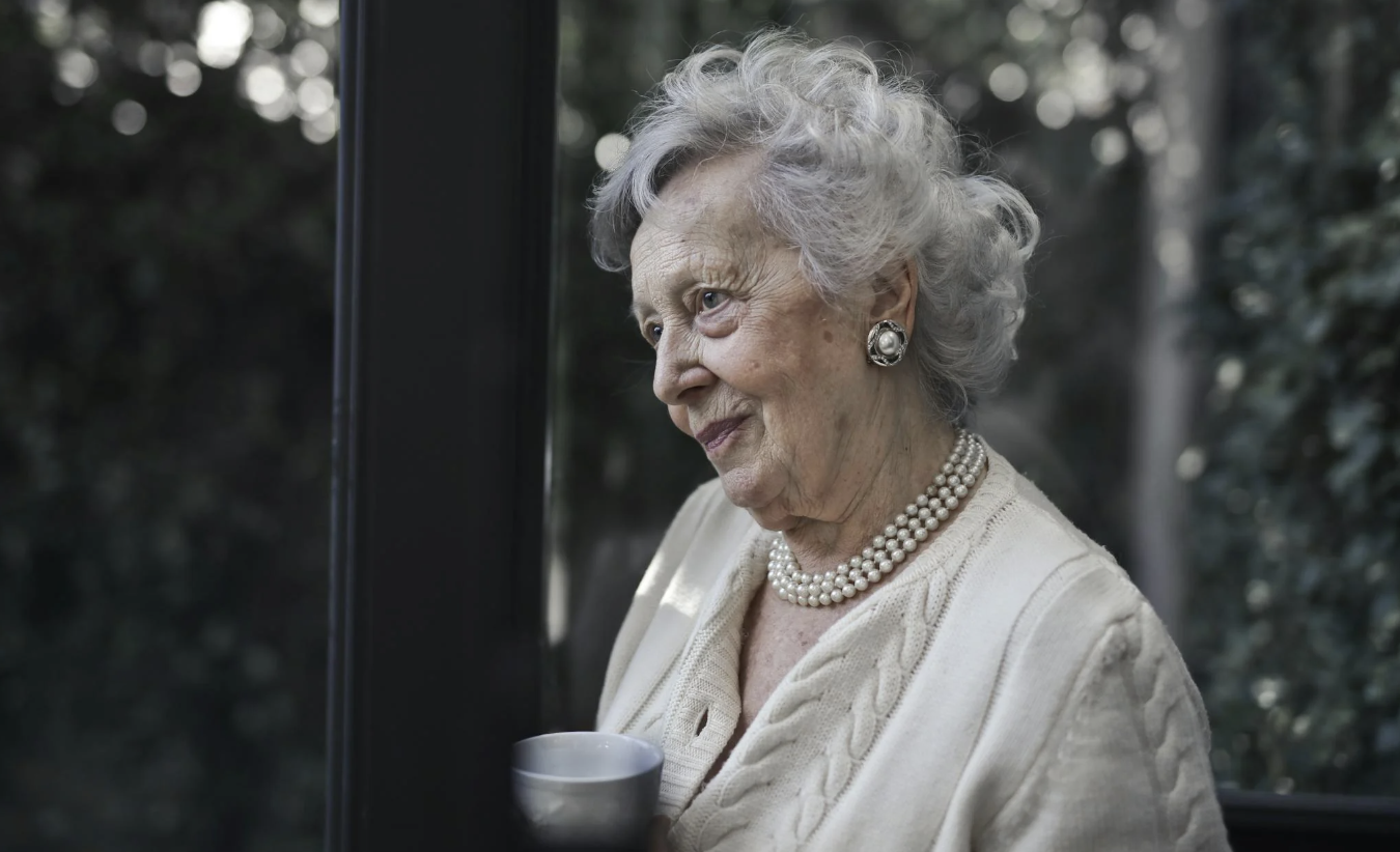 elderly woman looking out of a window