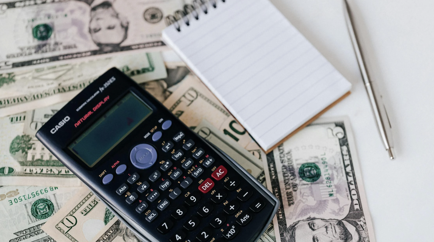 Notebook and calculator sitting on top of cash