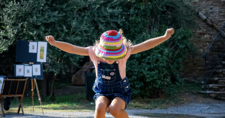 young girl jumping over puddle