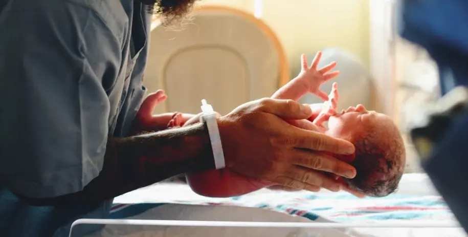 Newborn baby being gently held and cleaned by medical staff shortly after birth in a hospital setting