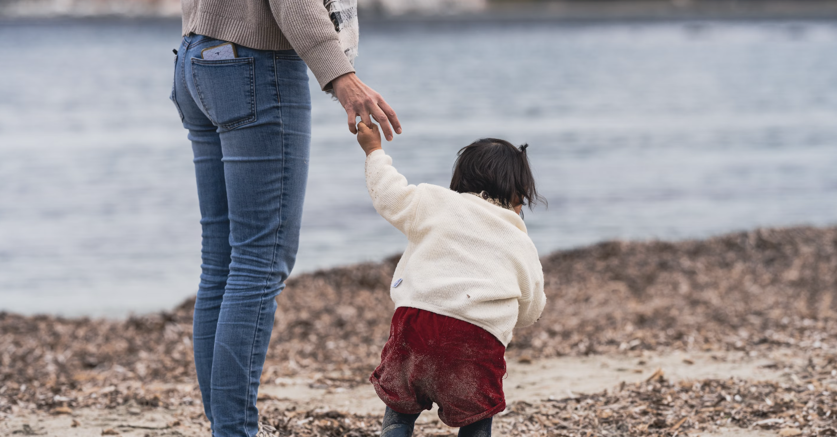 woman holding her adopted child's hand near the water