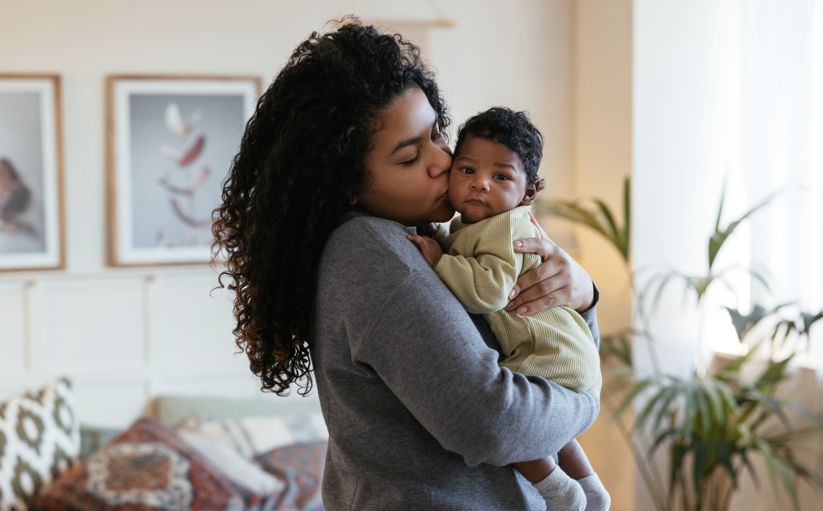 A young woman holding her baby in her home