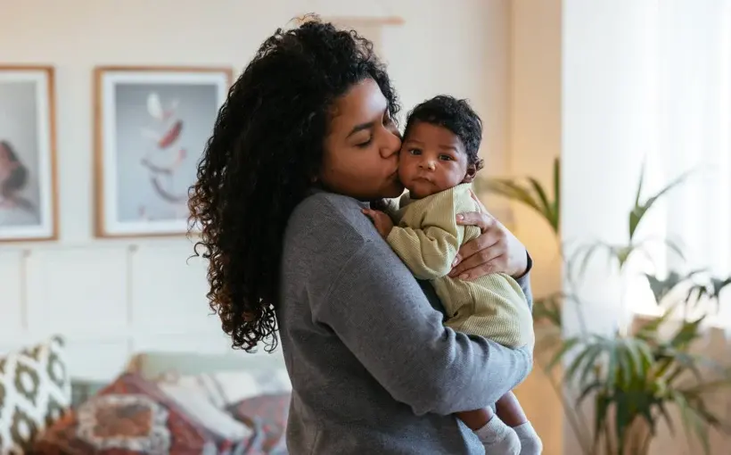 Mother holding her baby in a cozy home setting, creating a moment of affection and calm
