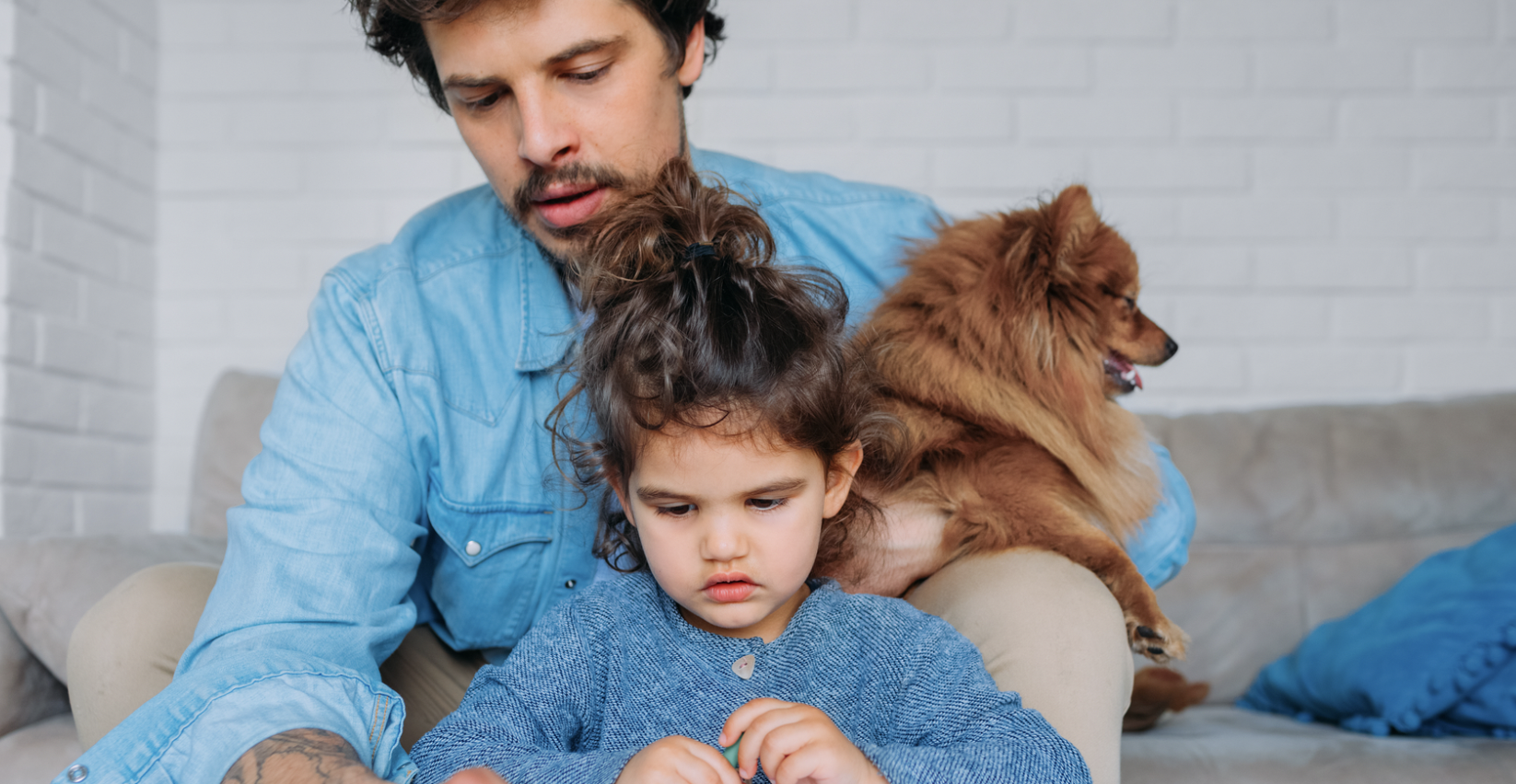 a father helping his daughter draw while holding the family dog