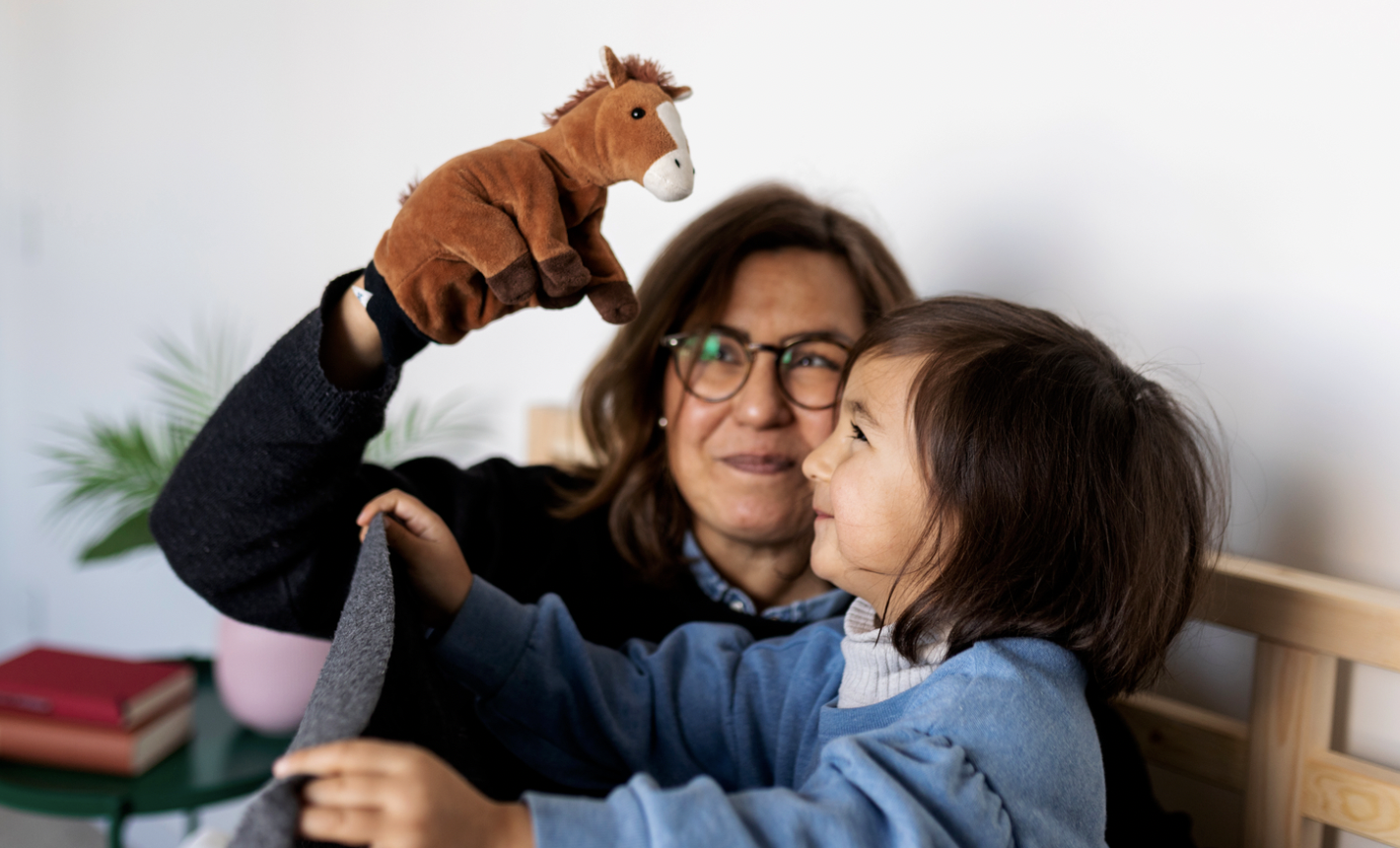 Grandmother holding up a horse toy to her granddaughter 